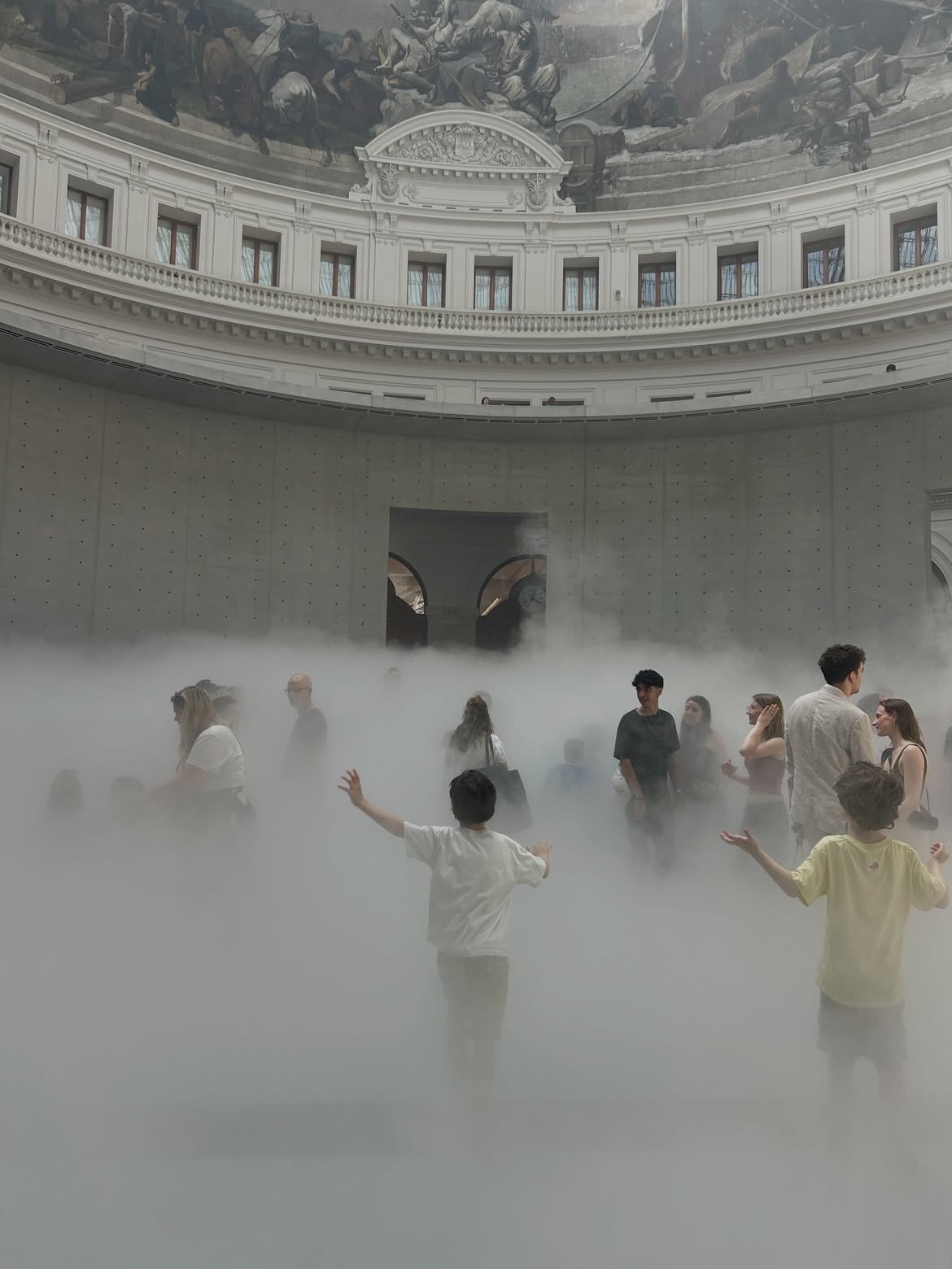 Visitors move through fog inside the Bourse de Commerce rotunda.